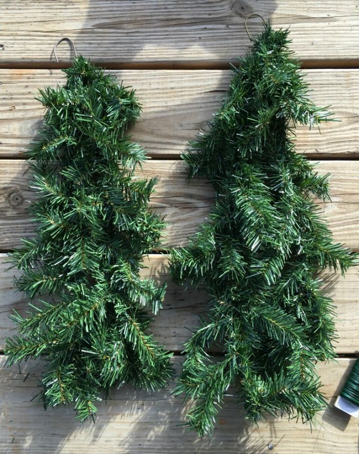 two green christmas trees sitting on top of a wooden table next to an empty bottle