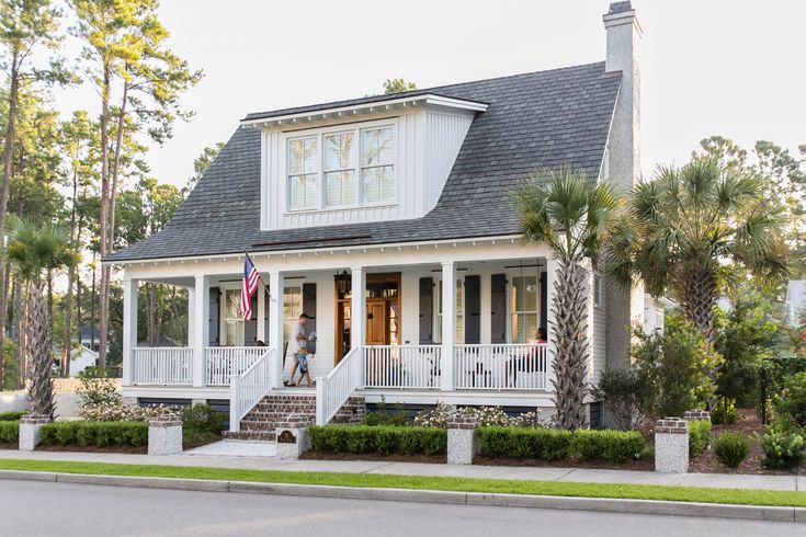 a white house with porches and trees in the front yard