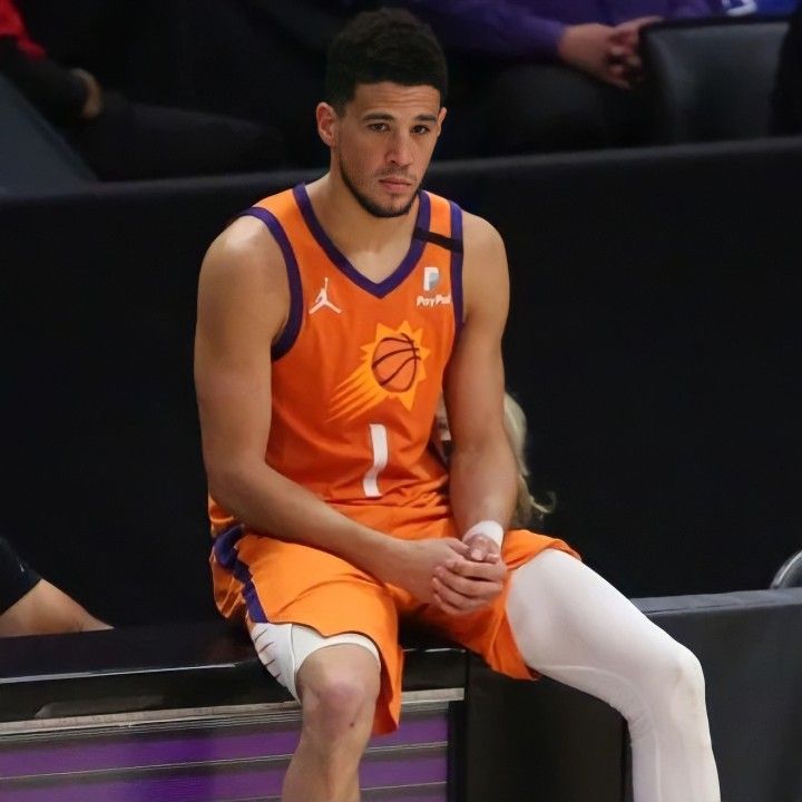 a man in an orange uniform sitting on a bench with his legs crossed and wearing white socks