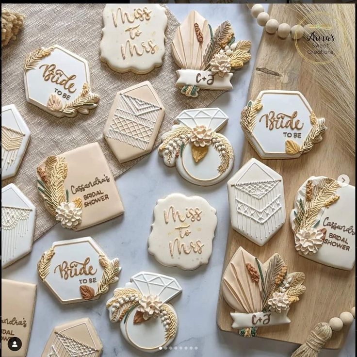 some decorated cookies are on a table with gold trimmings and white frosting