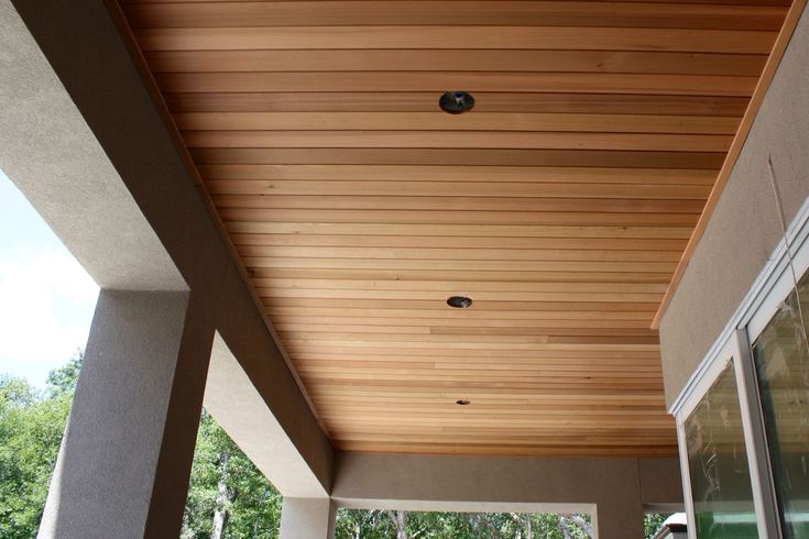 an outdoor covered patio with sliding glass doors and wood ceilinging on the side of it