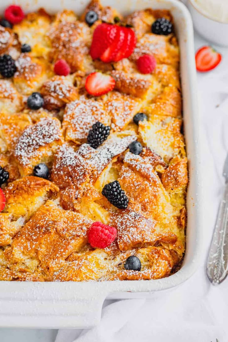 a casserole dish with berries and powdered sugar