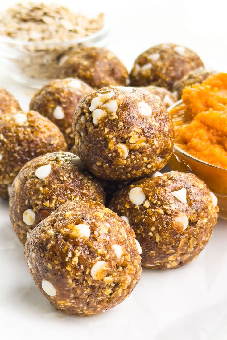 several balls of food sitting on top of a white plate next to bowls of carrots