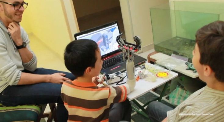 a man sitting next to a boy in front of a computer