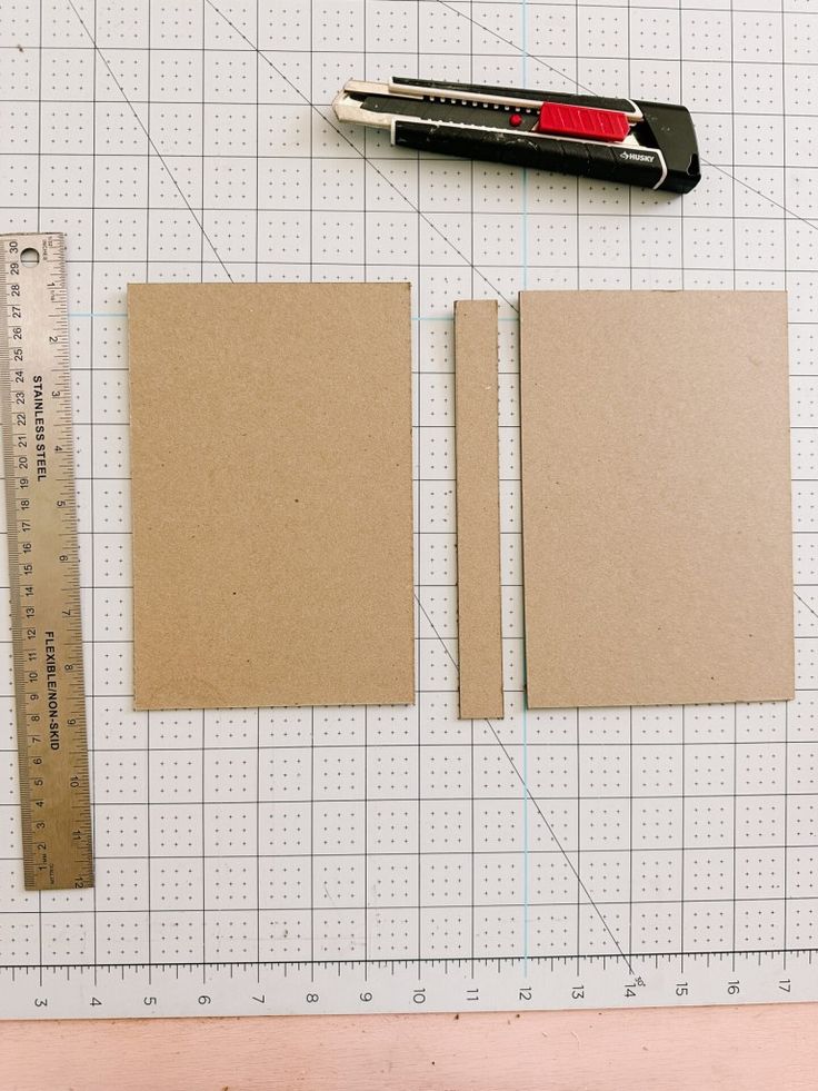 two pieces of brown paper are next to a ruler and pen on a cutting board