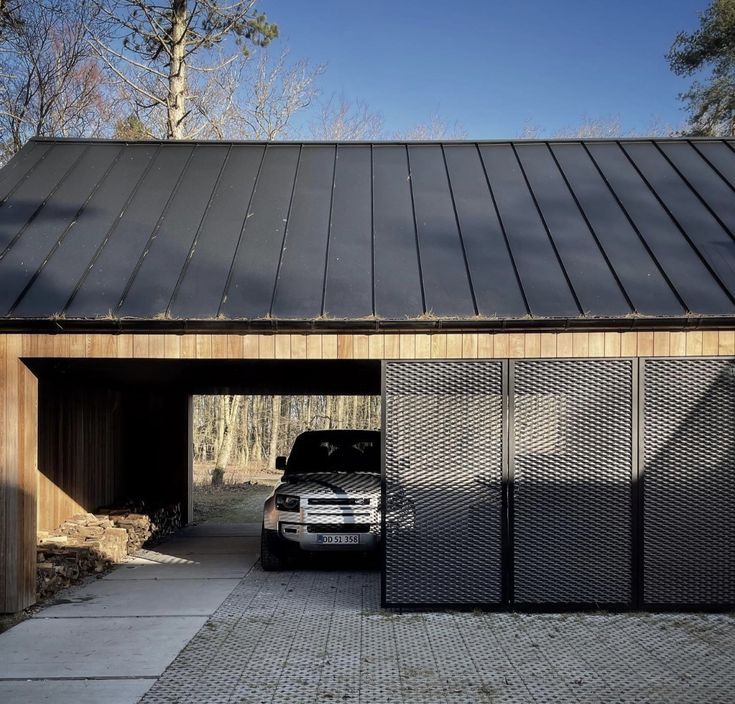 a car is parked in front of a garage with a metal roof and black gate