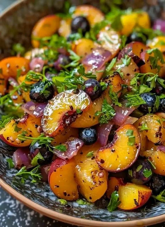 a salad with oranges, blueberries and parsley in a bowl on a table