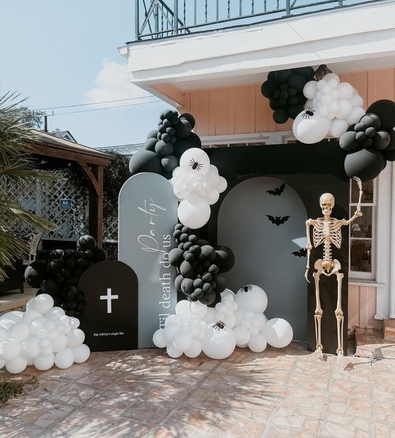 a skeleton is standing in front of a church decorated for halloween with balloons and decorations