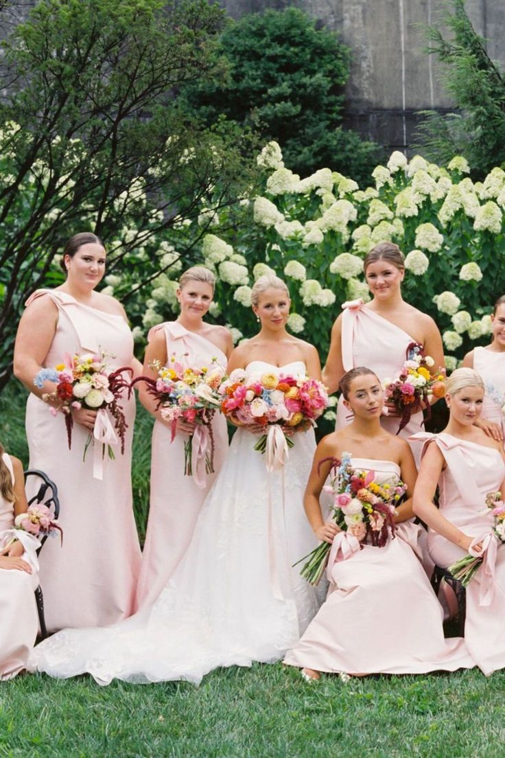 a group of bridesmaids in pink dresses posing for a photo