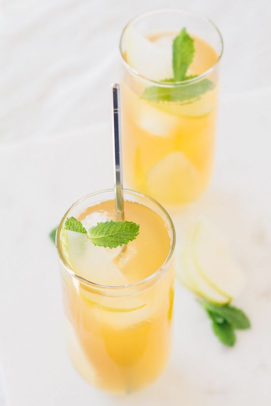 two glasses filled with lemonade and mint garnish on top of a table