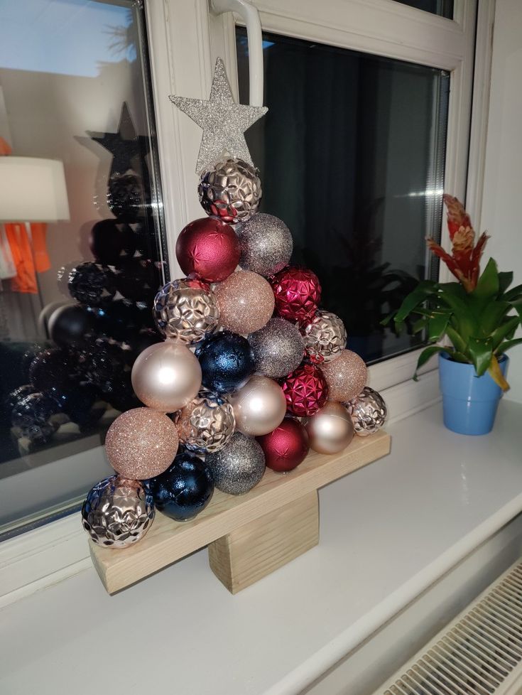 a christmas tree made out of ornaments on a window sill