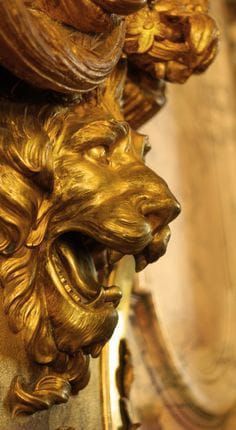 a golden lion head on the side of a wall