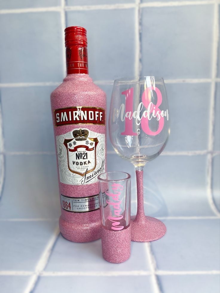 a bottle and two wine glasses sitting on a tile counter top next to each other