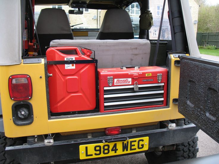 the back end of a yellow and black truck with red toolboxes in it