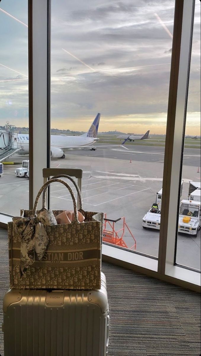 an airport terminal with luggage on the ground and planes in the background, from inside