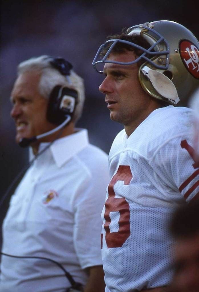 two football players standing next to each other on the sidelines with headphones in their ears