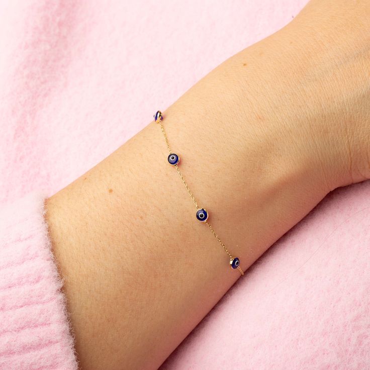 Our 14K Gold Evil Eye Bracelet is a blend of style and symbolism, inspired by the cultural heritage of the Turkish evil eye. This dainty bracelet, available exclusively in gold, features a choice of a blue or red evil eye charm, each known for its protective properties and cultural significance. The bracelet's delicate cable chain, with a thickness of 0.85 mm, is perfect for a subtle yet fashionable look and ideal for layering with other pieces. The adjustable length, ranging from 6.3" to 7.5", ensures a comfortable and versatile fit for various wrist sizes. Key Features: Cultural Symbol: Features a blue or red Turkish evil eye charm, known for its protective qualities and cultural significance. Delicate Design: Crafted with a slender cable chain, perfect for layering and versatile styling Gold Evil Eye Bracelet, Red Evil Eye, Evil Eye Protection, Turkish Evil Eye, Dainty Bracelet, Red Bracelets, Protection Bracelet, Delicate Design, Dainty Bracelets