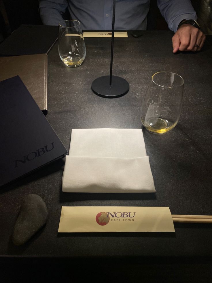 a man sitting at a table with some wine glasses and napkins on top of it