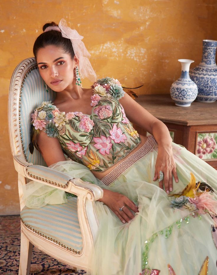 Editor's Note Featuring Varun Bahl's statement floral print in a tea green lehenga set. It includes a floral embroidered corset top embellished with 3-dimensional floral corsages, floral printed lehenga highlighted with sequin, cutdana and 3-dimensional floral petals. It is also paired with a tea green dupatta embellished with drops and corsages. Fabric: Chanderi and mono net Color: Green Component: Lehenga, blouse and dupatta Fit: Fitted at the bust & waist Occasion: Haldi mehndi Note: Product Green Floral Embellished Party Gown, Green Floral Party Gown, Fitted Gown With Floral Embroidery For Garden Party, Fitted Green Gown With Floral Applique, Green Floral Applique Wedding Gown, Green Wedding Gown With Floral Applique, Green Floral Embroidered Party Gown, Fitted Green Gown With Floral Embroidery, Green Floral Embroidery Party Gown