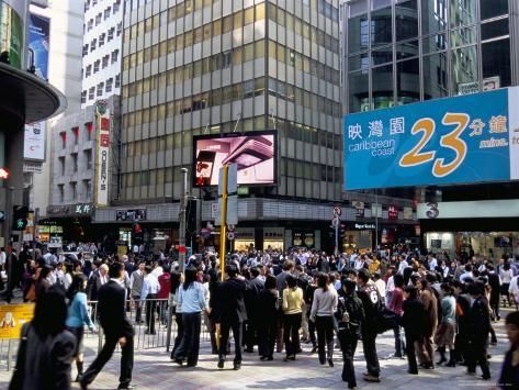 a large group of people standing in the middle of a busy city street with tall buildings