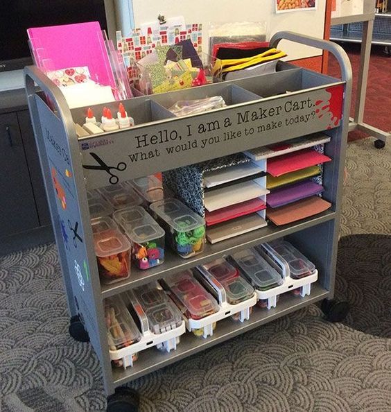 a cart filled with lots of crafting supplies on top of a carpeted floor