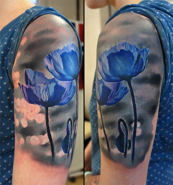 a blue flower tattoo on the left arm and half - sleeve, with clouds in the background