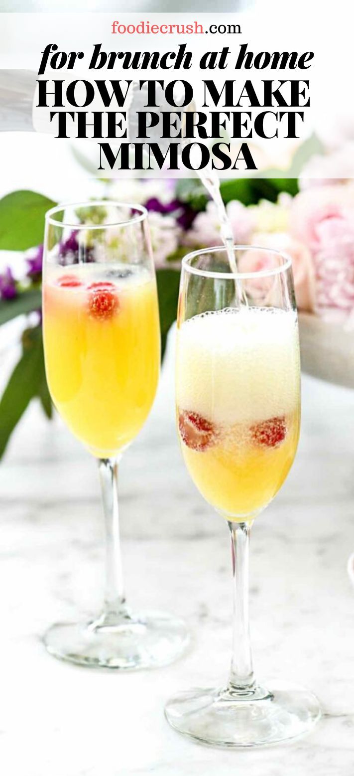 two glasses filled with drinks sitting on top of a white marble counter next to flowers