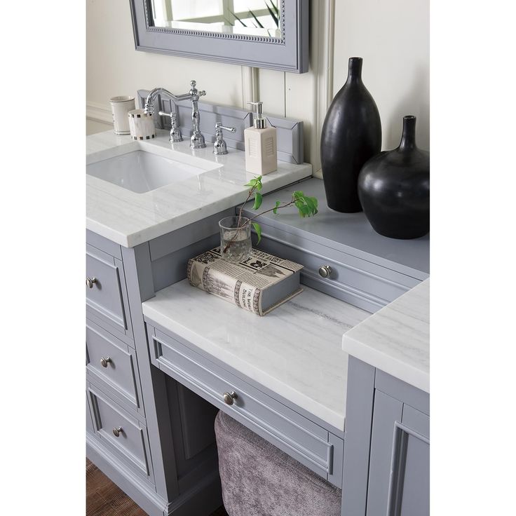 a bathroom vanity with two vases and a book on the sink counter next to it