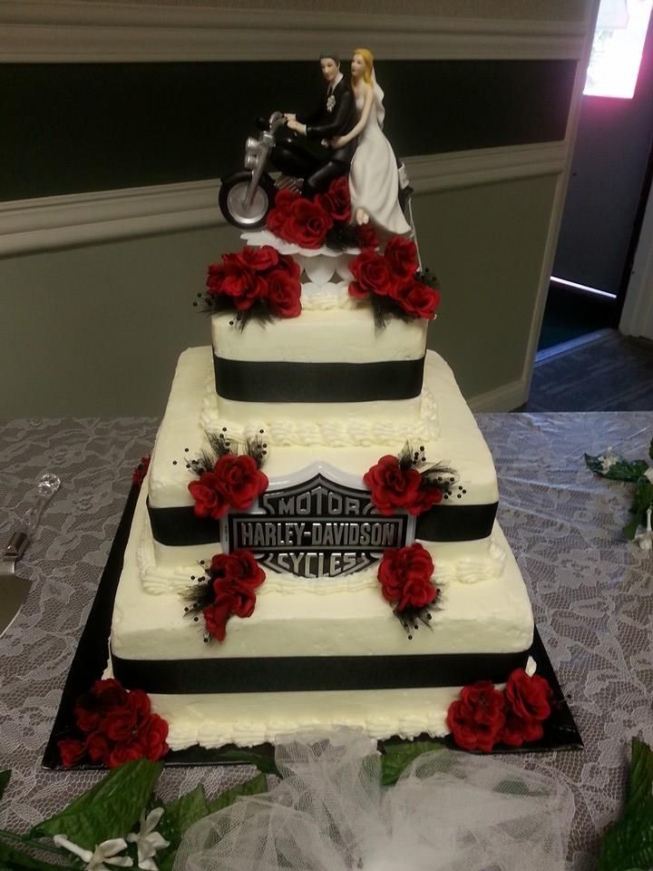 a wedding cake decorated with red roses and a motorcycle