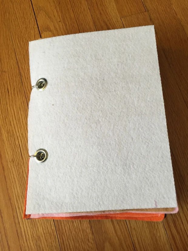 an orange and white binder sitting on top of a wooden floor