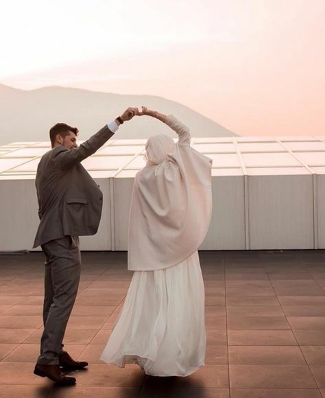 a man and woman dressed in muslim garb dance on the roof of a building