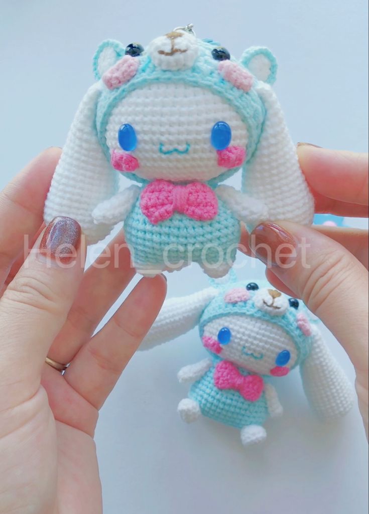 two small crocheted stuffed animals are being held by someone's hand with their fingers