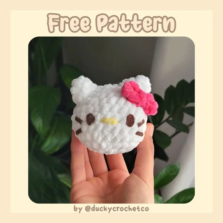 a hand holding a hello kitty crochet brooch