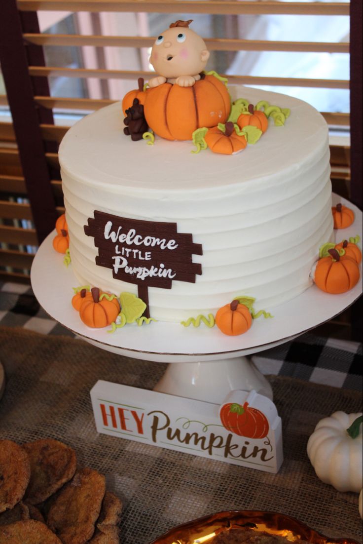 there is a white cake with pumpkins on it and a sign that says welcome little pumpkin