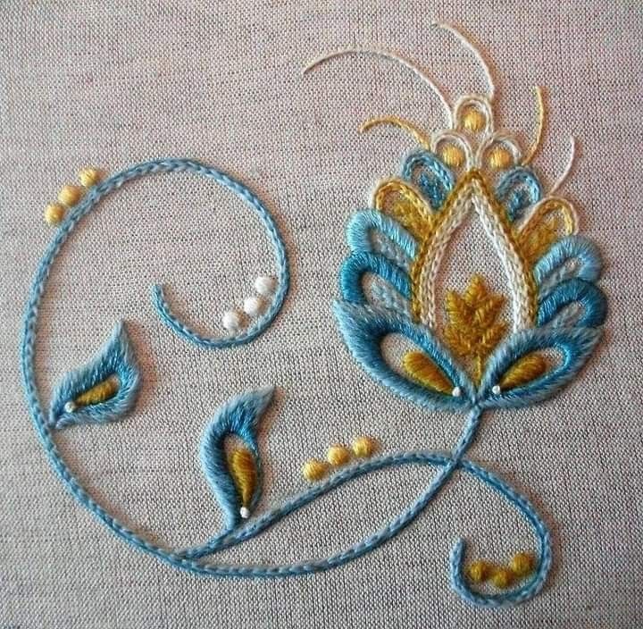 a close up of a piece of cloth with embroidery on it and some beads in the middle