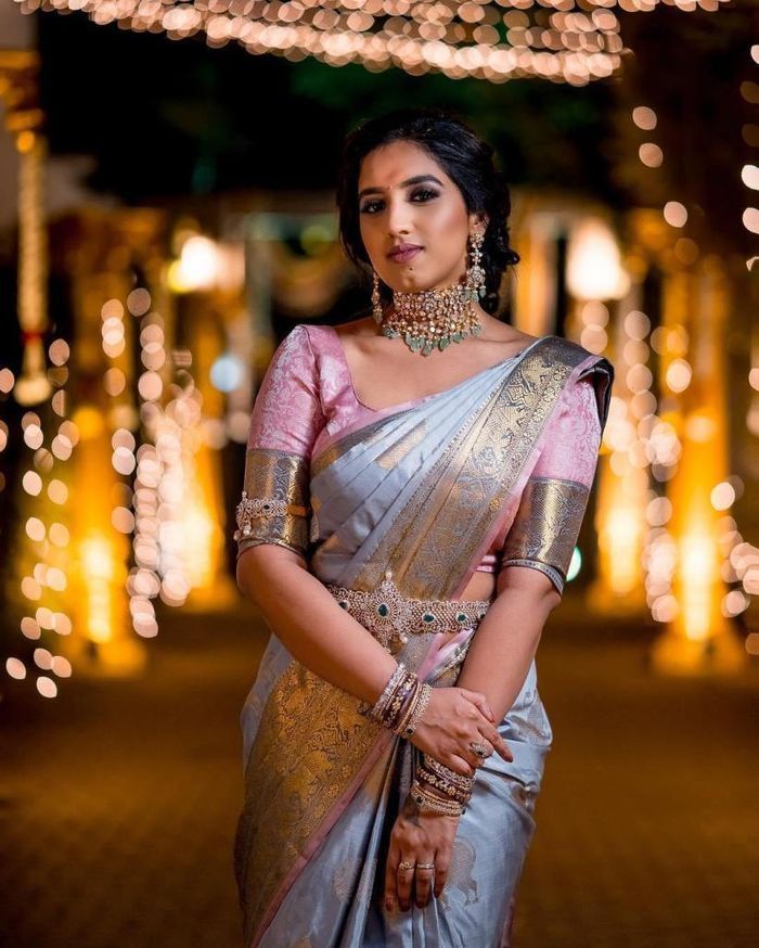 a woman in a sari posing for the camera with lights behind her and an archway