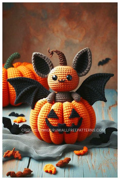 a crocheted bat sitting on top of a pumpkin with other bats around it