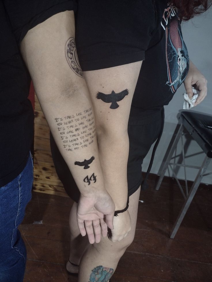 two people with tattoos on their arms and legs, one holding the other's hand