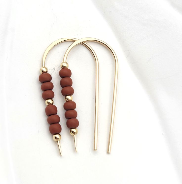 Adorn your ears with a touch of luxe! Our Cheval - Gold & Burnt Sienna Beads earrings are as classy and sophisticated as they come! Featuring a shimmering gold threader, they're decorated with deep, burnt sienna colored beads for a modern yet timeless look. 14k Gold Filled Measure approximately 1.25 Inches Quality Miyuki Seed Beads Sent in a Ribboned Gift Box Handmade in Montana Wire Jigs, Gift Box Handmade, Burnt Sienna, Open Hoop Earrings, Box Handmade, Beads Earrings, Fall Earrings, Delicate Earrings, Stunning Earrings