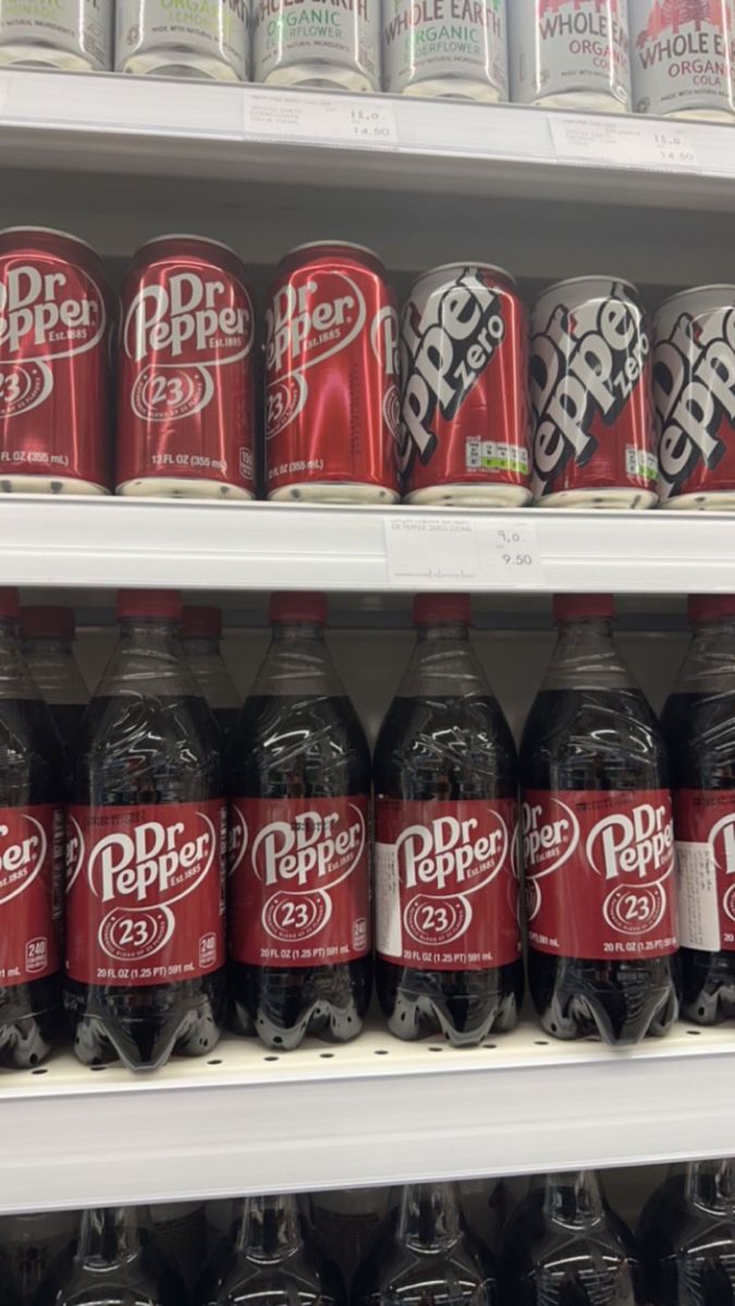 many cans of soda are on shelves in a grocery store, one is red and the other is black