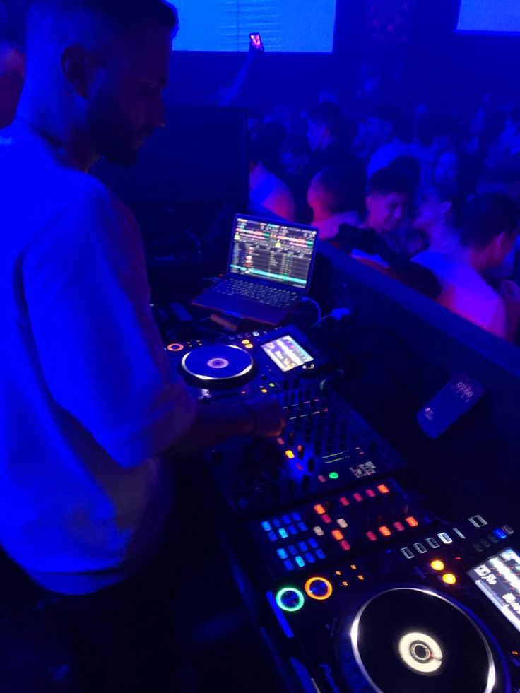 a dj mixing music in front of a large group of people at a club or nightclub