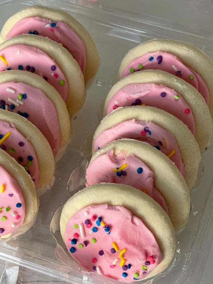 a plastic container filled with pink frosted donuts