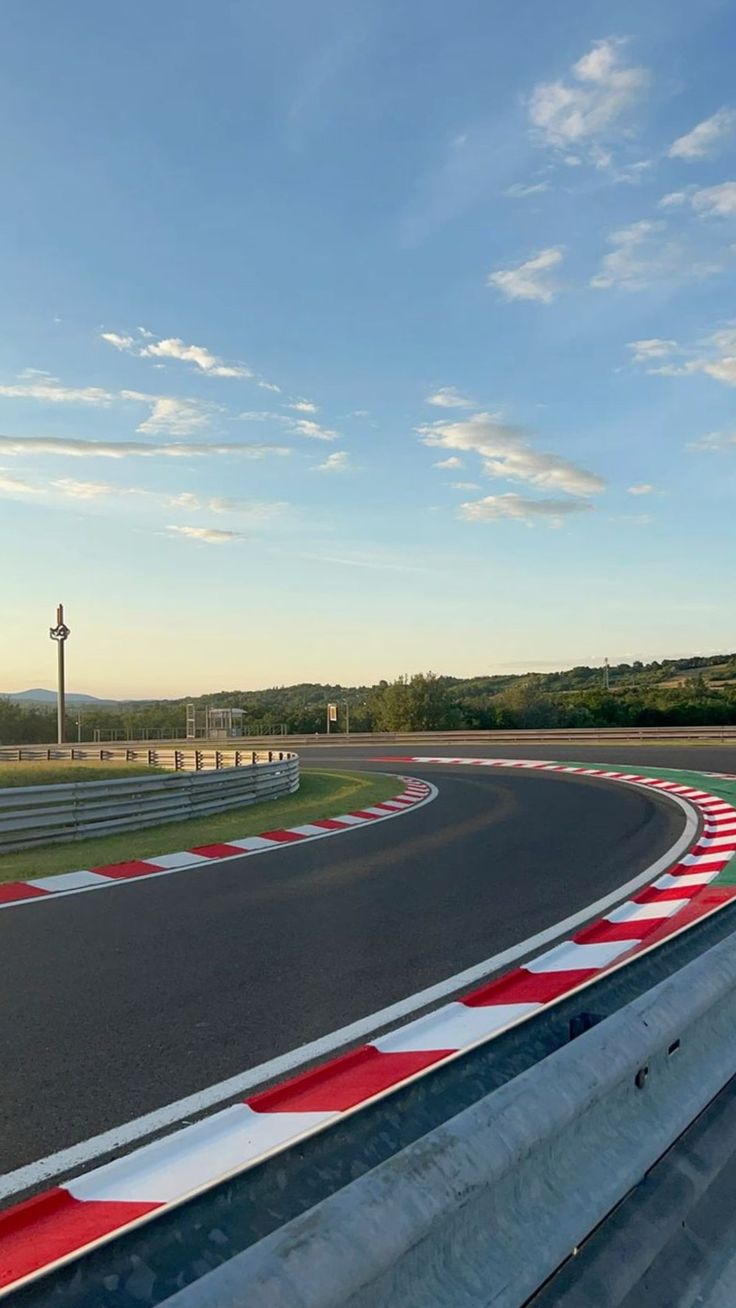 a person riding a motorcycle on a race track with red and white stripes down the side