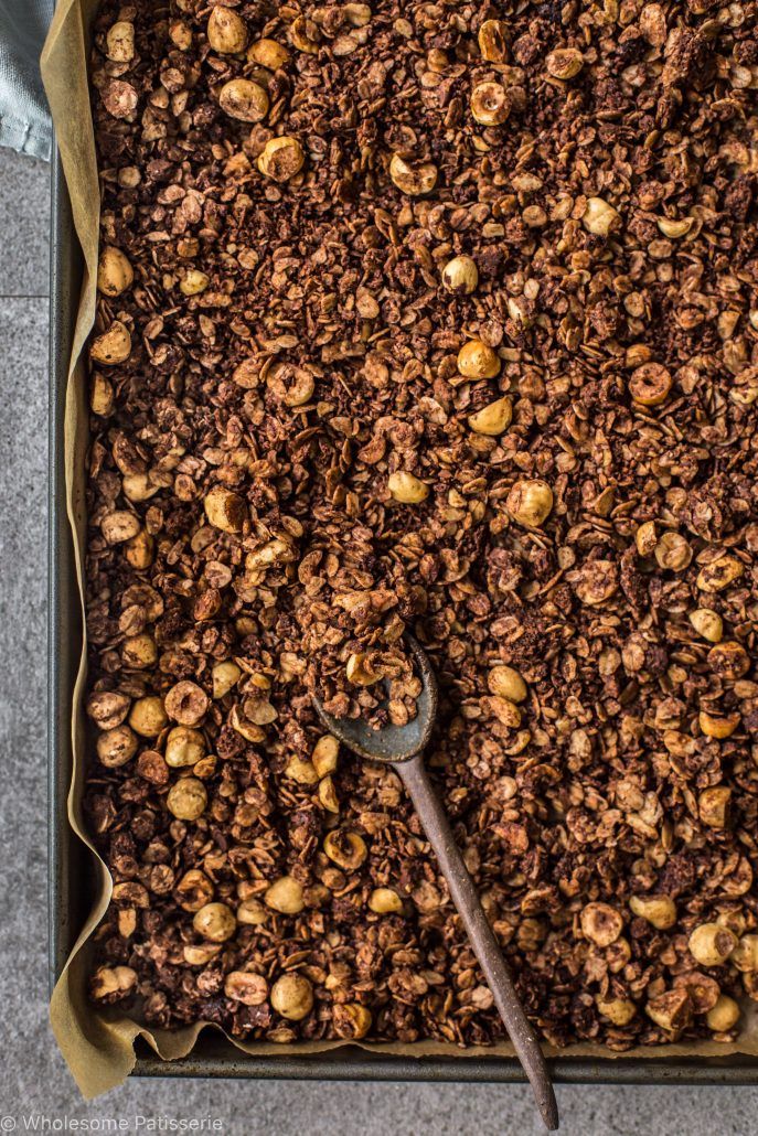 a baking pan filled with granola and a spatula on the side, ready to bake