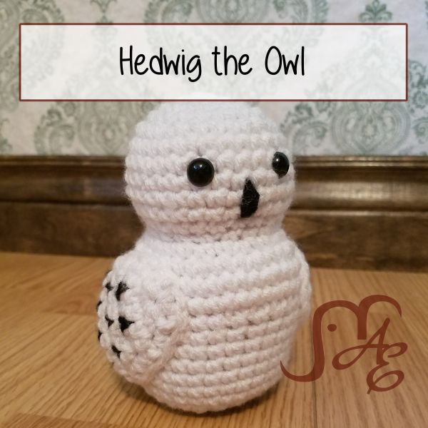 a crocheted owl sitting on top of a wooden floor next to a wall