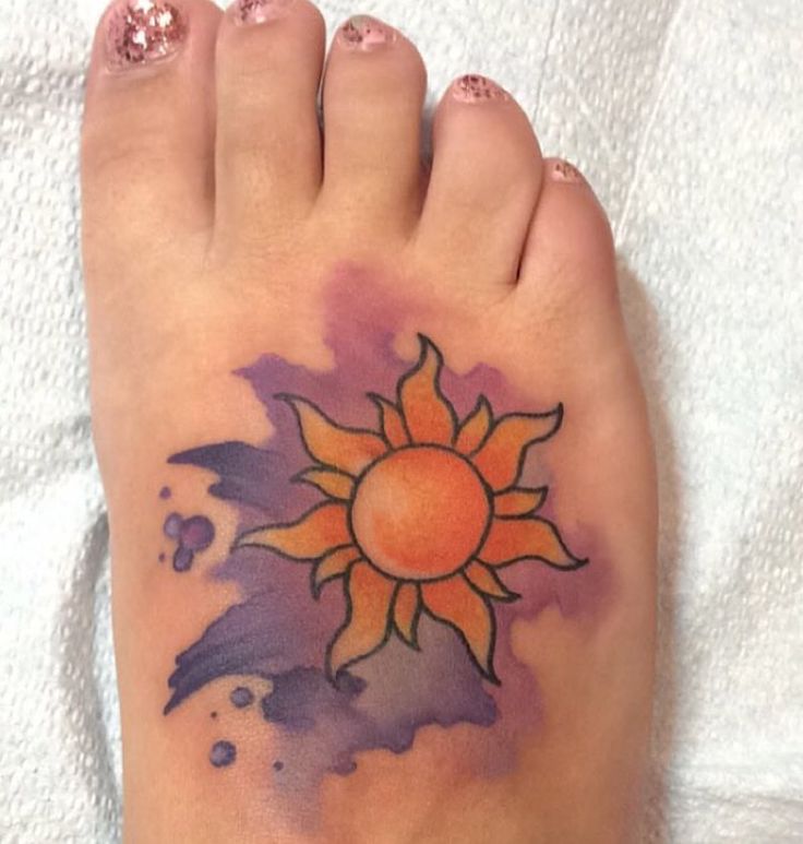 a person's foot with a sun tattoo on it