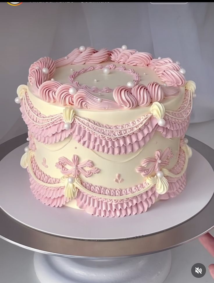 there is a pink and white cake on the table