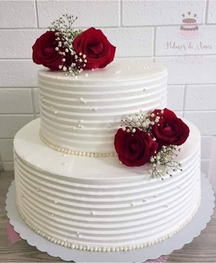 a three layer white cake with red roses on top