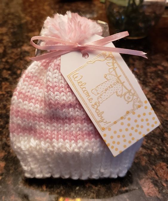 a pink and white knitted hat with a tag hanging from it's side