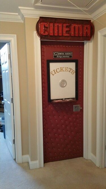 a cinema sign mounted to the side of a door in a room with carpeted flooring